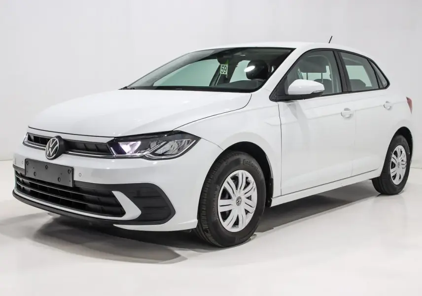 Volkswagen Polo blanche vue en 3/4 avant droit, avec phares allumés et jantes acier à enjoliveurs.