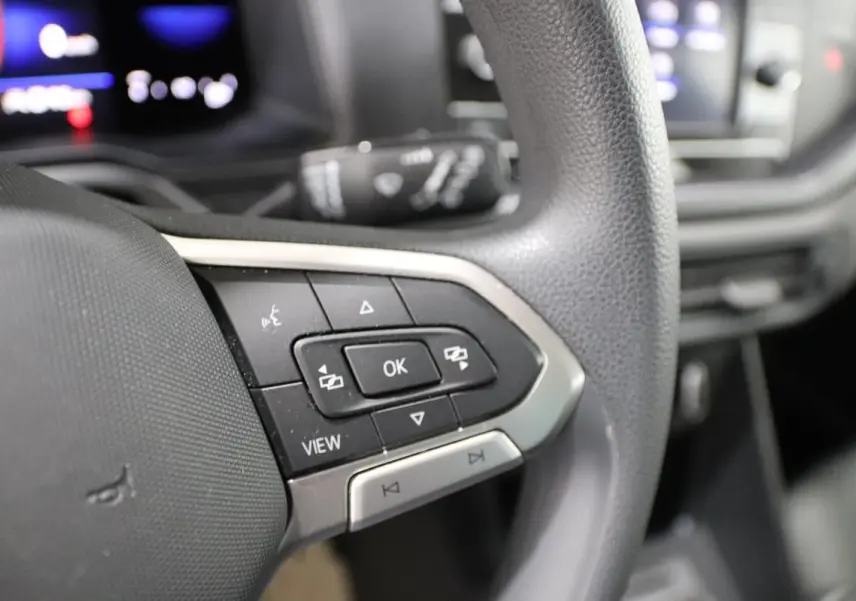 Gros plan sur les commandes multifonctions à gauche du volant noir de la Volkswagen Polo blanche, version 2022.