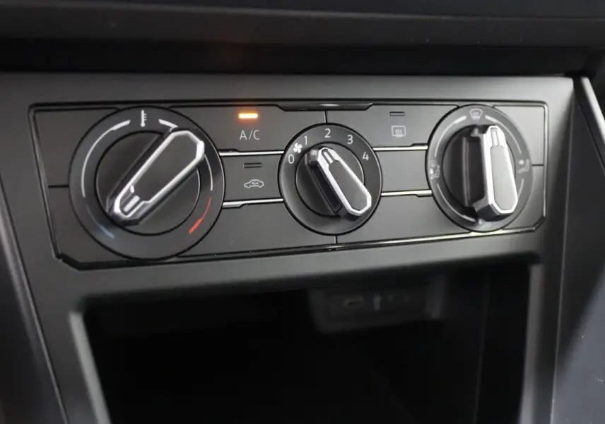 Gros plan sur les commandes de climatisation manuelle du Volkswagen Polo 1.0 blanc, avec témoin A/C allumé.