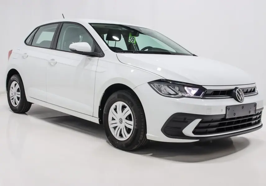 Volkswagen Polo blanche vue en 3/4 avant droit, avec phares allumés et jantes en acier à enjoliveurs.