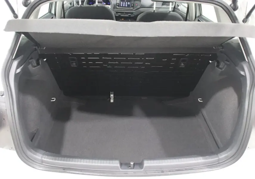 Coffre ouvert vue arrière d’une Volkswagen Polo blanche 2022, intérieur du coffre spacieux et tapis noir.