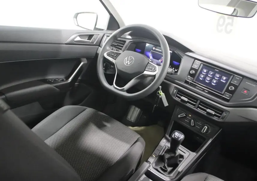 Vue intérieure côté conducteur de la Volkswagen Polo blanche 2022, avec volant multifonction et boîte manuelle visible.