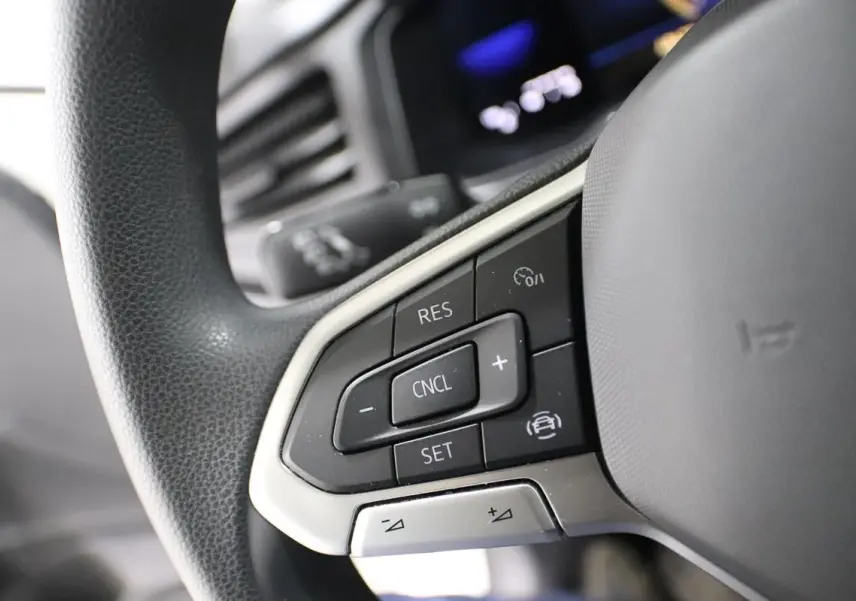 Gros plan sur les commandes de régulateur de vitesse au volant noir d'une Volkswagen Polo blanche de 2022.