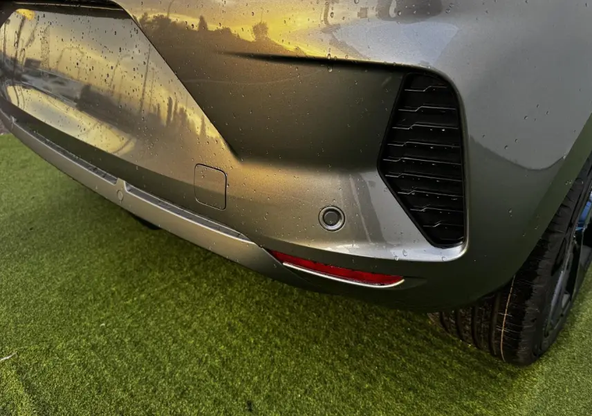 Gros plan sur le pare-chocs arrière droit gris schiste métallisé de la Renault Clio V avec capteur de stationnement et feu rouge.