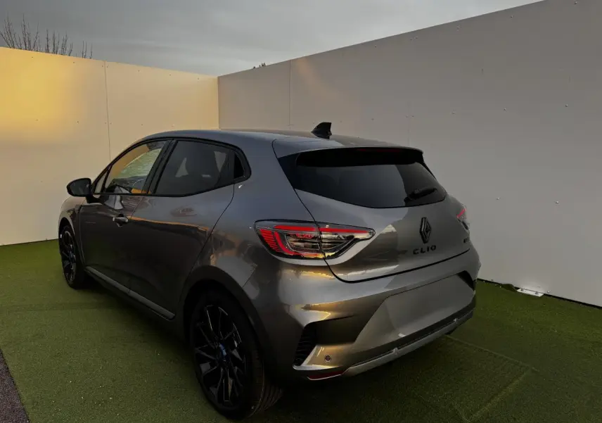 Renault Clio V hybride gris schiste vue 3/4 arrière droit, jantes alliage noires et vitres teintées.