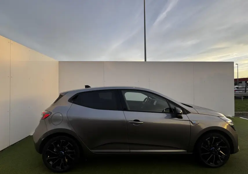 Profil côté gauche de la Renault Clio V hybride gris schiste métal avec jantes noires et vitre teintée.