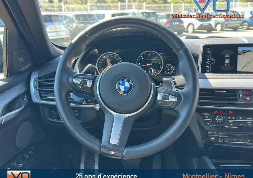 Intérieur BMW X6 F16 M Sport 2017, volant cuir sport, tableau de bord avec écran GPS et caméra de recul visible.