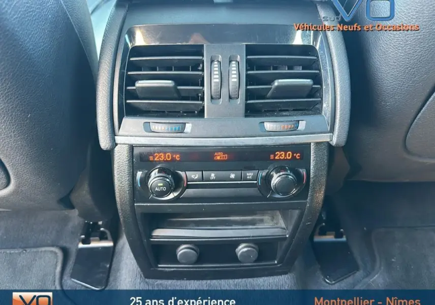 Détail de la console arrière avec commandes de climatisation et aérateurs sur BMW X6 F16 noir de 2017.