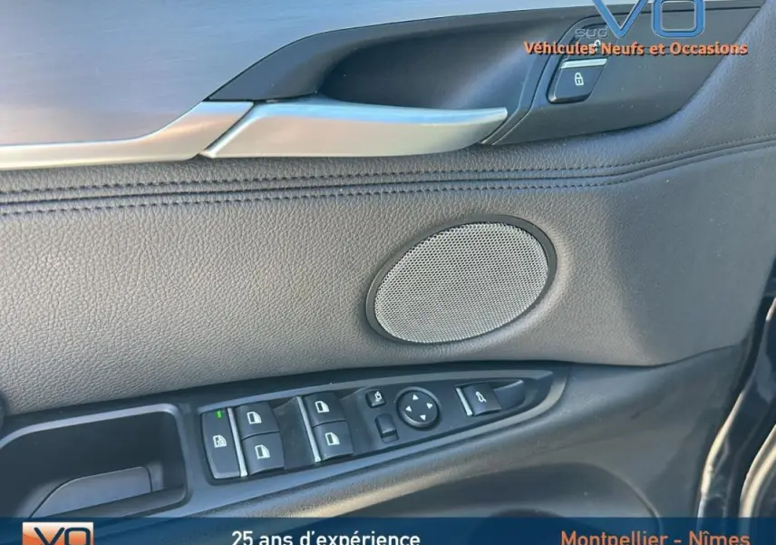 Détail de la porte côté conducteur en cuir noir avec commandes électriques et haut-parleur sur BMW X6 F16 noir.