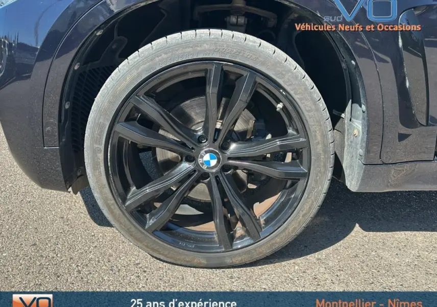 Gros plan sur la jante alliage noire 19 pouces du BMW X6 F16 noir, mettant en valeur le logo BMW central.