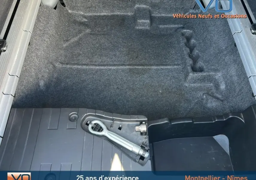 Vue plongeante sur le coffre vide d'un BMW X6 noir F16 xDrive40d 2017, avec tapis et outil de remorquage visible.