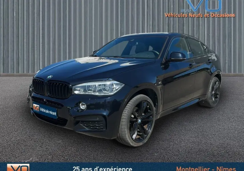 BMW X6 F16 xDrive40d noir en 3/4 avant droit, avec jantes alliage noires et phares bi-xénon allumés.