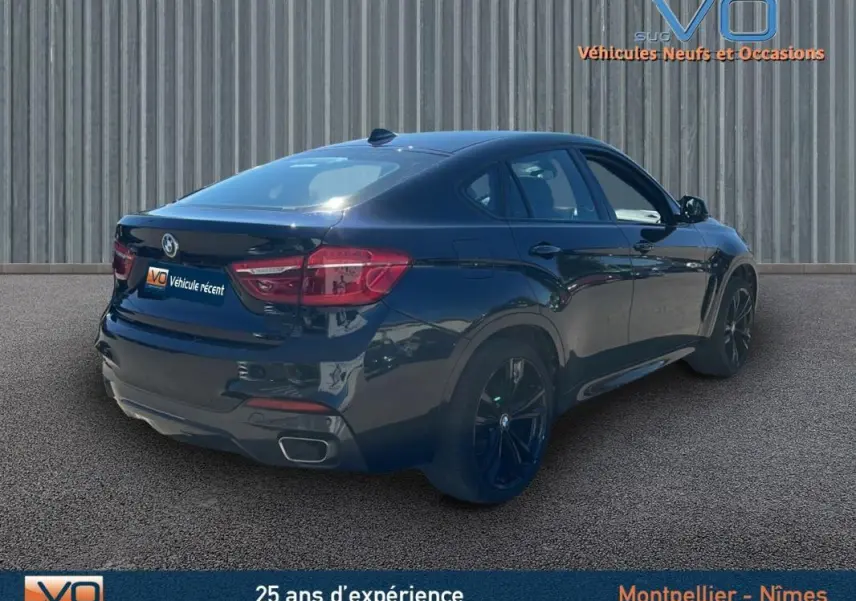 BMW X6 F16 noir en 3/4 arrière droit, mettant en valeur ses jantes alliage noires et sa silhouette coupé SUV élégante.