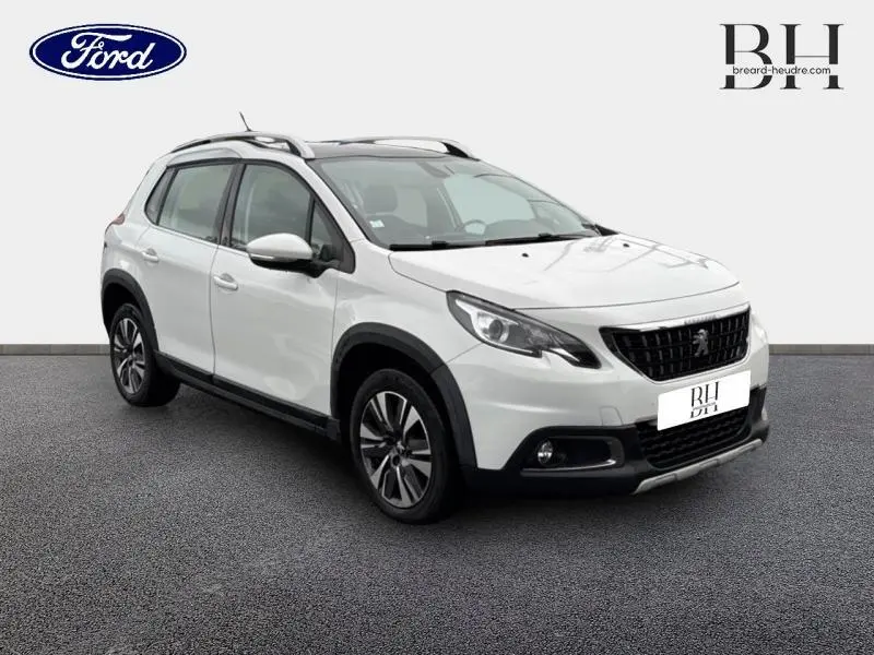 Peugeot 2008 blanc banquise vue 3/4 avant droit, avec barres de toit et jantes alliage visibles.