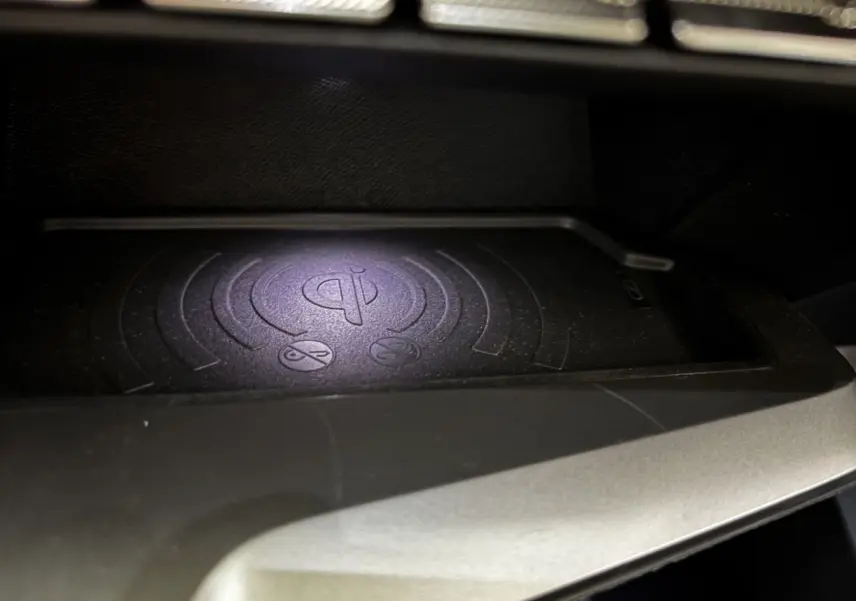 Gros plan sur le chargeur sans fil Qi intégré dans la console centrale de la Peugeot 308 Hybrid 145 e-DCS6 Allure.