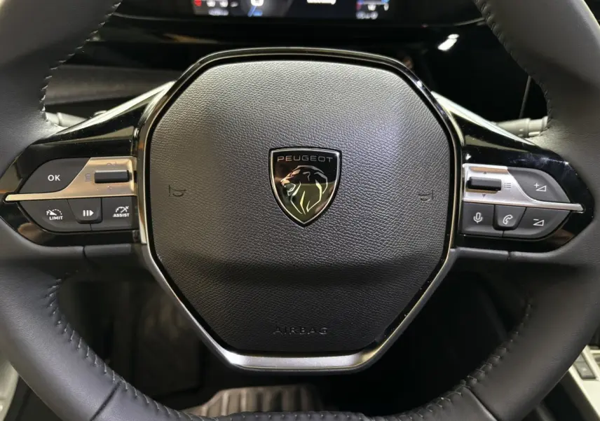 Gros plan sur le volant cuir noir multifonctions de la Peugeot 308 Hybrid 145 e-DCS6 Allure 2025.
