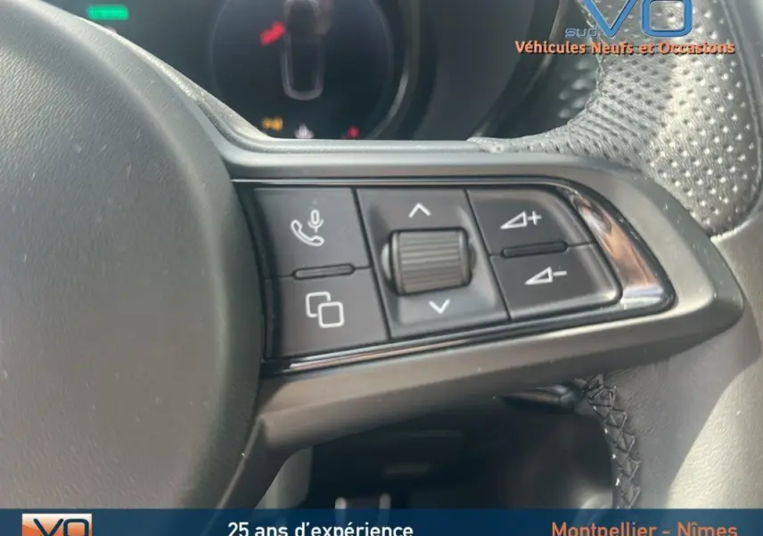 Gros plan sur les commandes du volant sport de l'Alfa Romeo Tonale rouge 2024, avec molette et boutons multifonctions.