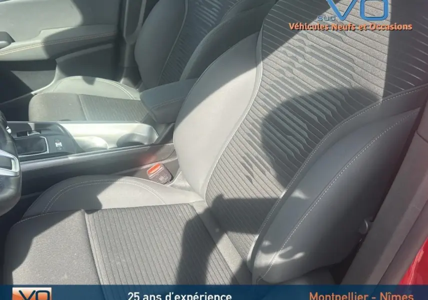 Vue rapprochée des sièges avant gris foncé de l'Alfa Romeo Tonale rouge, mettant en valeur l'accoudoir central et la console.