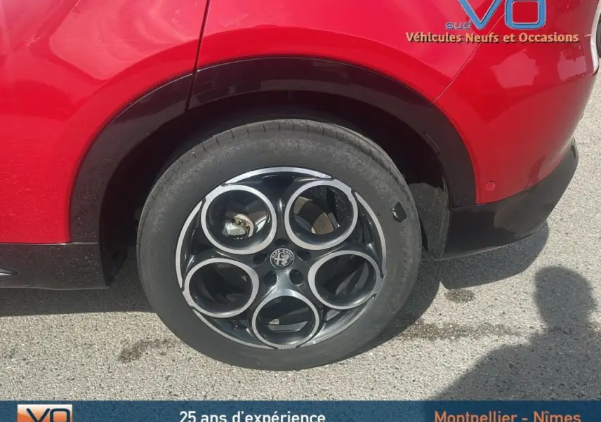 Gros plan sur la roue arrière droite rouge d'une Alfa Romeo Tonale 1.5 Hybrid Sprint avec jante noire à cercles argentés.