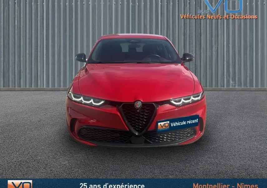 Vue frontale d'une Alfa Romeo Tonale rouge 2024 avec phares LED allumés et calandre caractéristique en V.