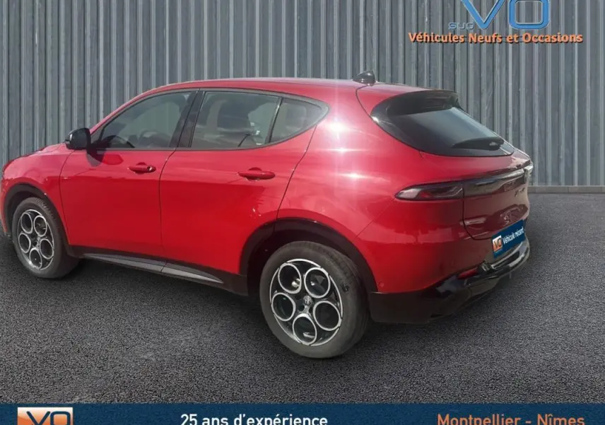 Vue 3/4 arrière gauche d'un Alfa Romeo Tonale rouge 2024 avec jantes distinctives et vitres teintées.