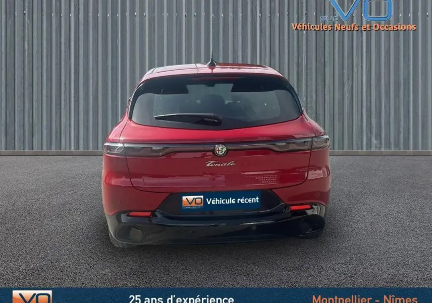 Vue arrière d'une Alfa Romeo Tonale rouge 2024 avec feux effilés et logo central sur fond urbain.