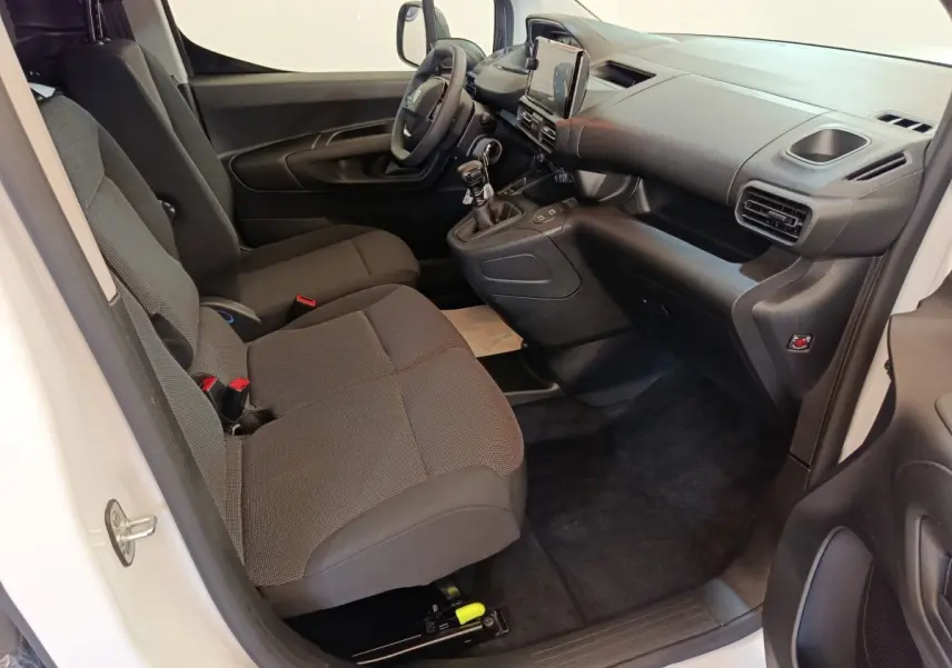 Vue intérieure côté conducteur du Peugeot Partner blanc 2026, montrant sièges tissu gris et tableau de bord moderne.