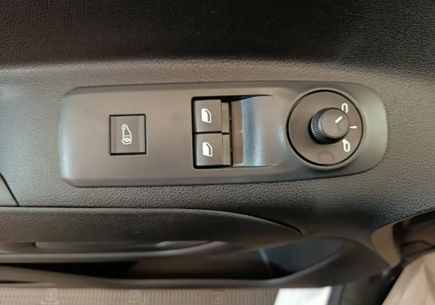 Vue rapprochée des commandes de réglage des rétroviseurs et vitres électriques sur la porte côté conducteur d’un Peugeot Partner blanc.