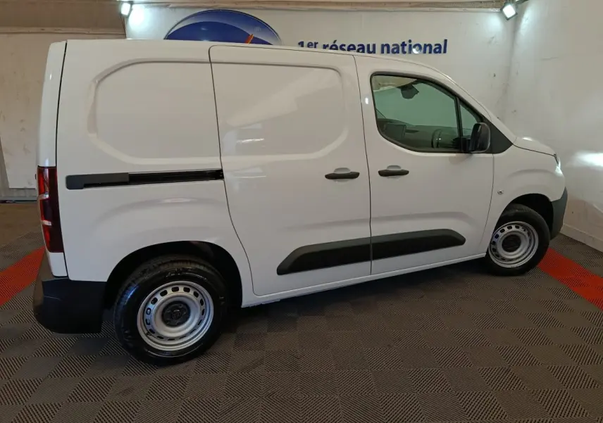 Vue de profil côté droit d’un utilitaire Peugeot Partner blanc, avec portes latérales pleines et jantes acier simples.