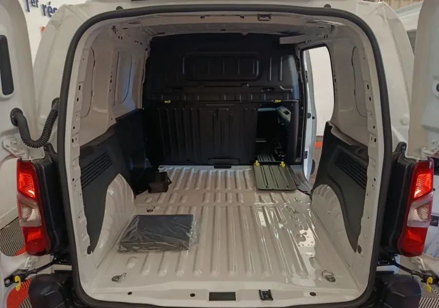 Vue arrière ouverte du Peugeot Partner blanc 2026 montrant l'espace de chargement vide avec cloison pleine noire.