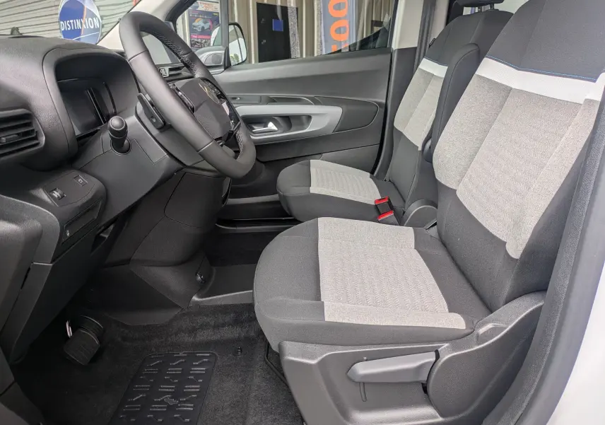 Vue intérieure côté conducteur du Citroën Berlingo blanc 2025, montrant les sièges avant bicolores et le tableau de bord.