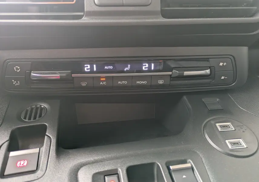 Détail du tableau de bord du Citroën Berlingo blanc 2025 montrant la climatisation automatique à 21°C et commandes USB.