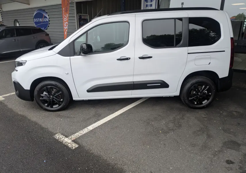 Vue de profil côté gauche d'un Citroën Berlingo blanc 2025 avec jantes noires et protections latérales noires.