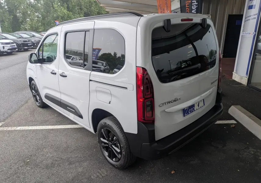 Vue 3/4 arrière droite d'un Citroën Berlingo blanc 2025 avec jantes noires et vitres teintées, stationné en extérieur.