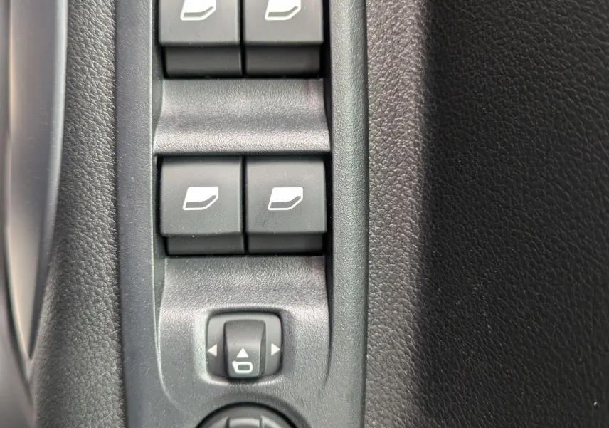Vue rapprochée des commandes de lève-vitres et réglage des rétroviseurs sur la porte intérieure noire du Citroën Berlingo blanc 2025.