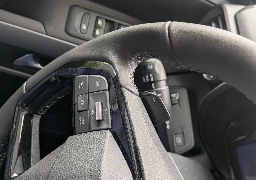 Gros plan sur le volant côté gauche du Citroën Berlingo blanc 2025, avec commandes intégrées et partie du tableau de bord.
