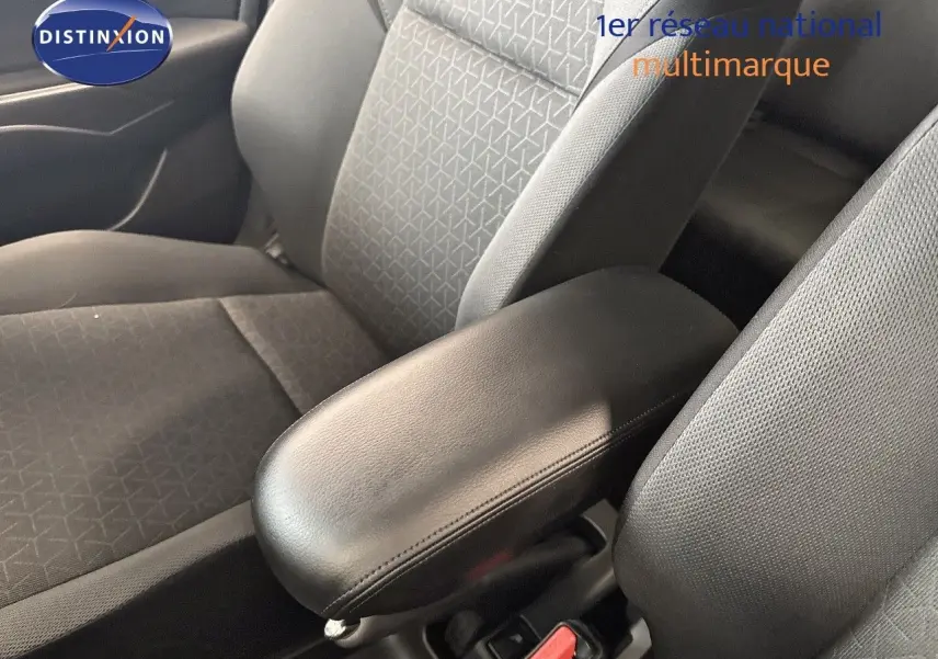 Gros plan sur l'accoudoir central noir et les sièges avant gris foncé à motifs dans l'habitacle d'une Suzuki Swift 2024.