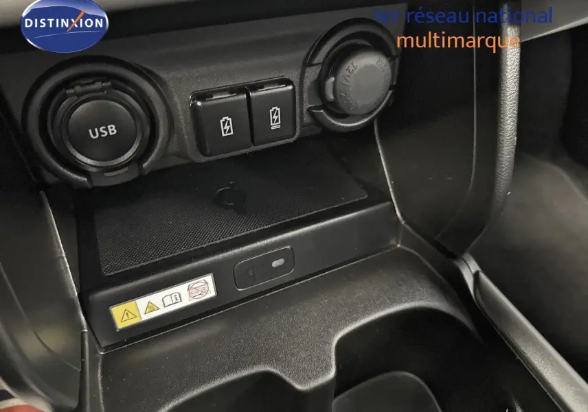 Gros plan sur la console centrale noire de la Suzuki Swift 1.2 Pack Hybrid 2024, montrant prises USB et ports de charge.