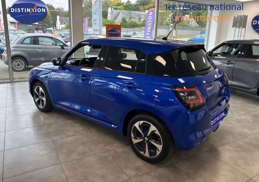 Suzuki Swift 1.2 Pack Hybrid bleu vue 3/4 arrière droit en intérieur, avec jantes alliage et vitres teintées.