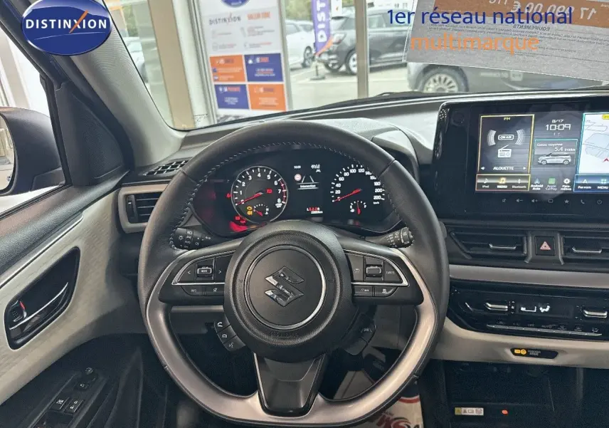 Vue intérieure centrée sur le volant et le tableau de bord de la Suzuki Swift 1.2 Pack Hybrid 2024, avec écran tactile et commandes au volant.
