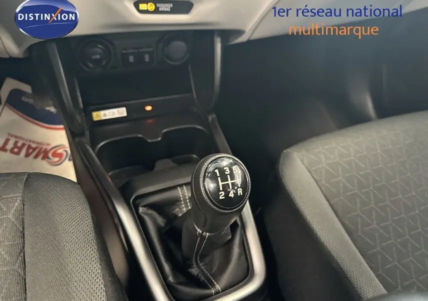 Gros plan sur le levier de vitesse manuel noir de la Suzuki Swift 1.2 Pack Hybrid 2024, intérieur tissu gris.