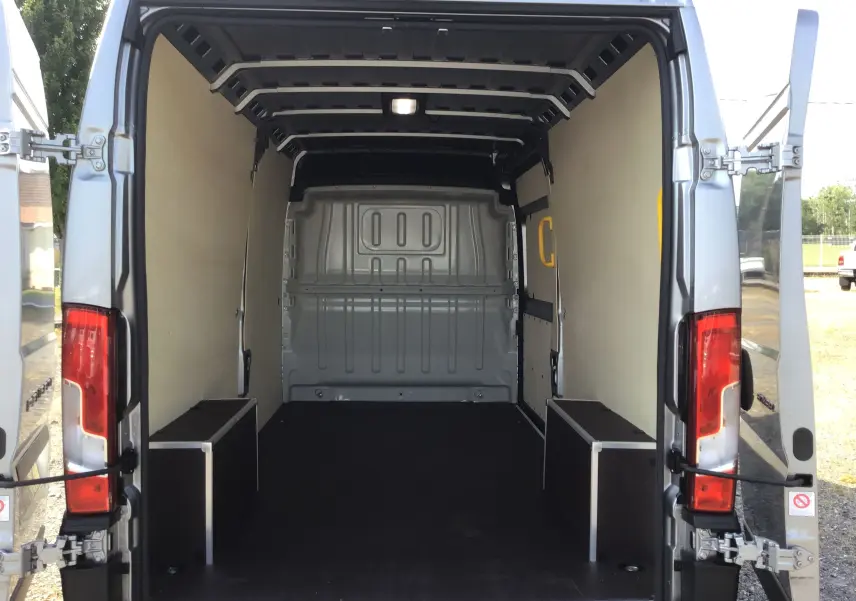 Vue arrière du Peugeot Boxer Fourgon gris Artense 2025, portes ouvertes sur l'espace de chargement vide et aménagé.