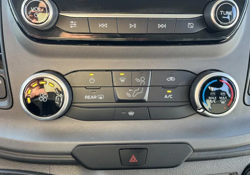 Vue rapprochée de la console centrale du Ford Transit Custom blanc 2021, montrant les commandes de climatisation et audio.