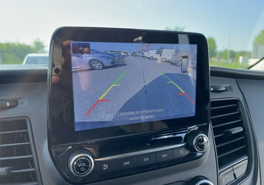 Écran tactile intérieur du Ford Transit Custom blanc de 2021 montrant la caméra de recul avec guidage coloré.
