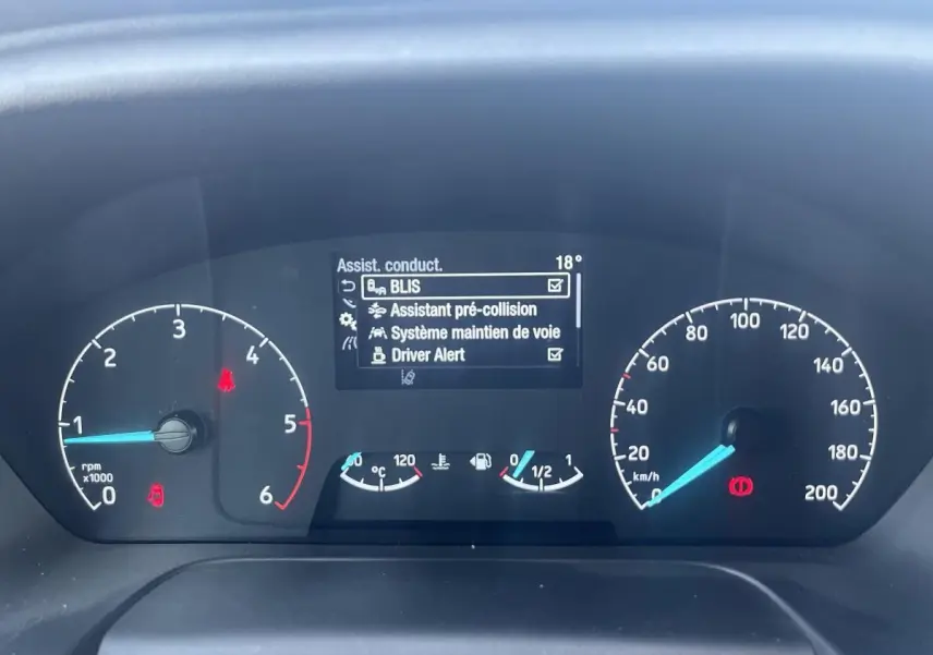 Tableau de bord du Ford Transit Custom blanc 2021 montrant les compteurs et l'écran d'assistance à la conduite.