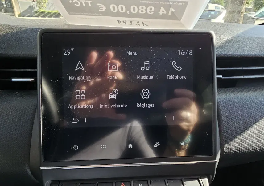 Écran tactile central du tableau de bord de la Renault Clio blanche, affichant le menu multimédia et navigation.