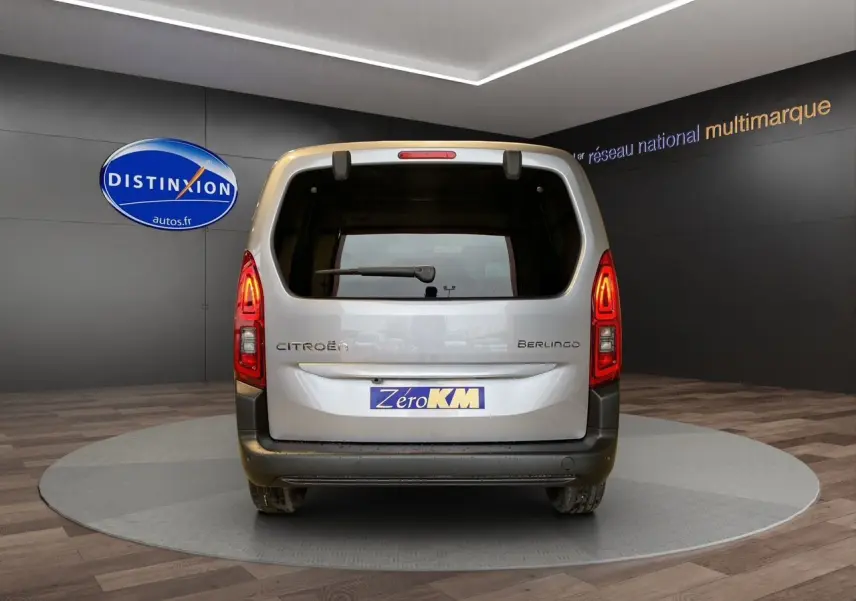 Vue arrière du Citroën Berlingo gris Artense 2025 avec hayon et feux arrière allumés en intérieur showroom.