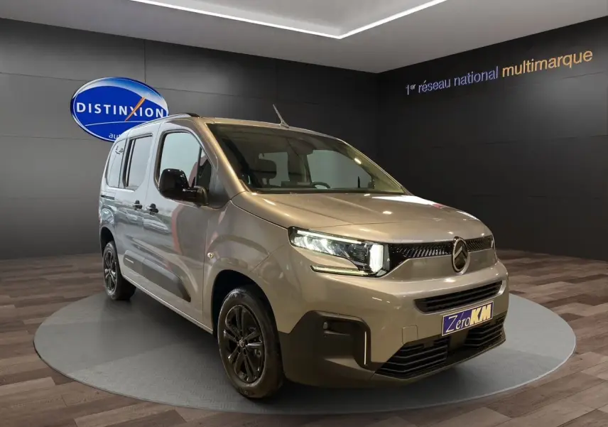 Citroën Berlingo Gris Artense en 3/4 avant droit avec jantes noires et caméra de recul visible en showroom.