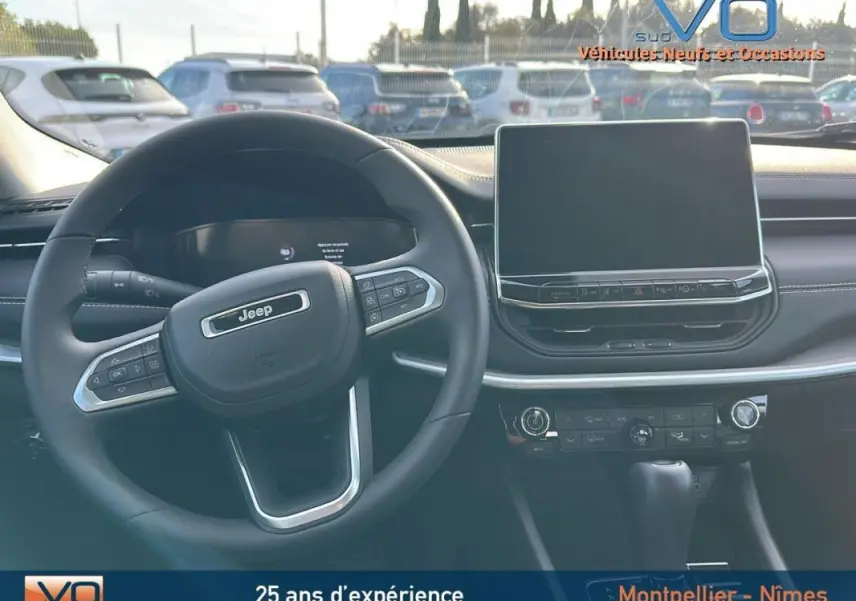 Vue intérieure du tableau de bord et volant noir du Jeep Compass 2024 avec écran tactile et commandes au volant visibles.