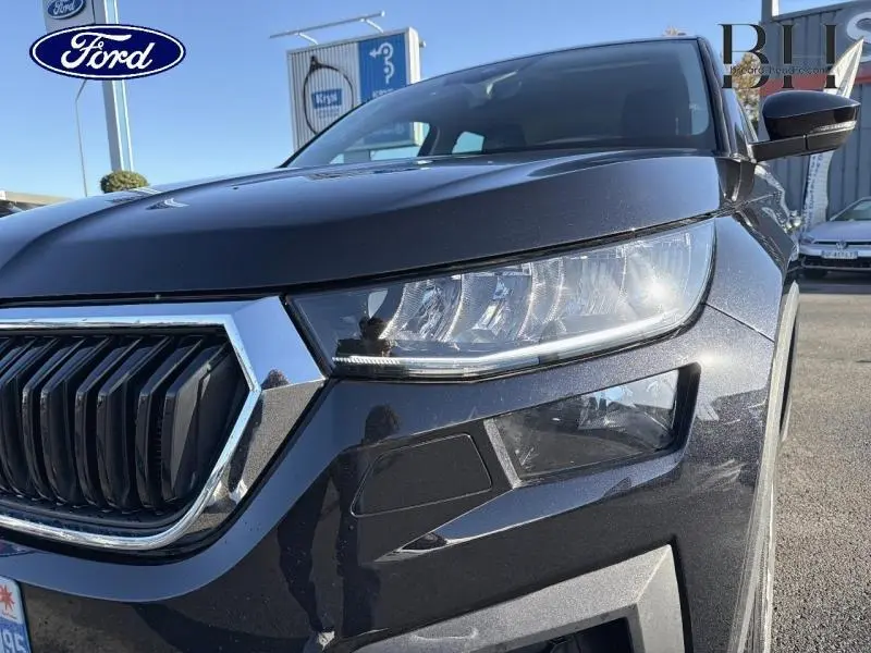 Gros plan sur le phare avant droit et la calandre chromée du Skoda Kodiaq noir Magic Nacré 2023.